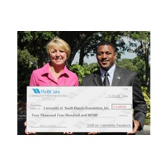 WellCare�s chief pharmacy officer, Laura Hungiville, presents Dr. Kevin Sneed, dean of the college of pharmacy, University of South Florida, with $4,400 to fund the college�s White Coat Ceremony.