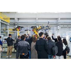 Observers watch industrial robots working based on instructions wirelessly transmitted at high speeds via 5G-Advanced indoor base stations