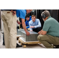 Researchers Brad Theilman, center, and Felix Wang, behind, unpack a neuromorphic computing core at Sandia National Laboratories... Read Complete caption below. (Photo by Craig Fritz)