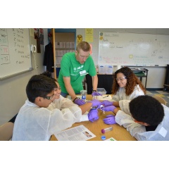 BASF employee Brad Cook watches as 8th grade students from East Wake Middle School filter water samples using different filtration techniques.