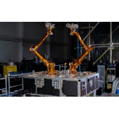 Two robotic arms wrapped in gold material sitting on top of a black and silver box.
Naval Research Laboratory